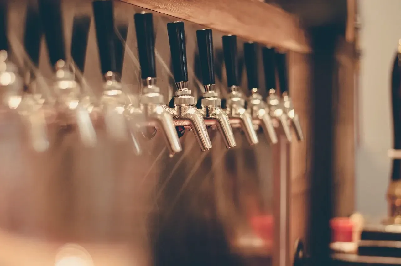 Row of chrome beer taps along a wooden bar