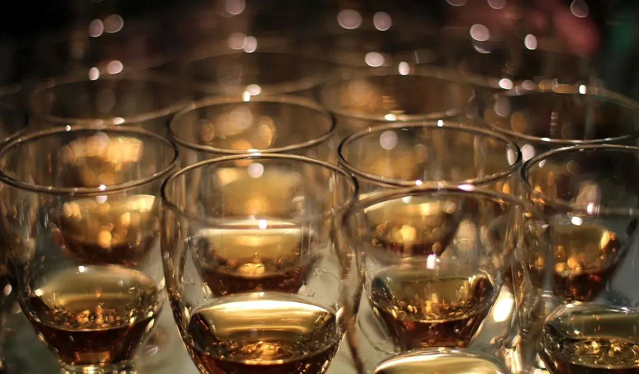 Rows of whiskey glasses glowing amber under bar lights